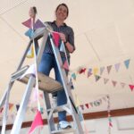 Wedding planner on ladders putting flags up